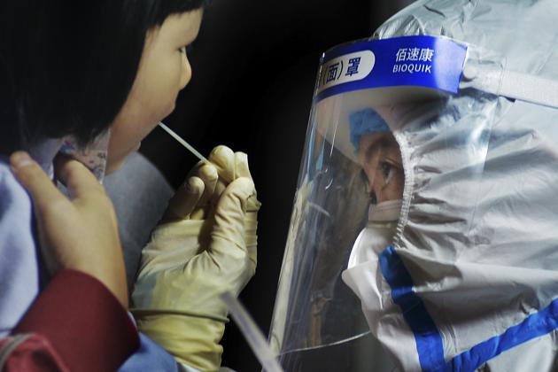 A medical staff takes a swab from a child near a residential area in Qingdao in east China's Shandong province(AP) A medical staff takes a swab from a child near a residential area in Qingdao in east China's Shandong province(AP)