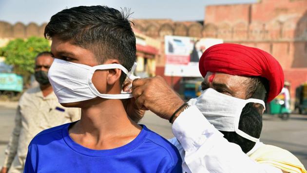 A social worker puts a face mask on a boy in the wake of coronavirus pandemic during an awareness drive, in Bikaner. (PTI) A social worker puts a face mask on a boy in the wake of coronavirus pandemic during an awareness drive, in Bikaner. (PTI)