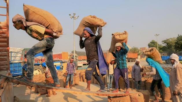 Labourers load sacks of newly harvested paddy crop on a truck purchased at a grain market, in Bathinda on October 13. An early paddy harvest season was witnessed this year in the two food bowl states because of a long dry period that started in early September and sooner paddy procurement as a result are among causes of increased farm fires this year. (PTI)
