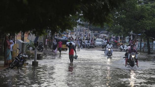 Commuters wade through receding floodwaters after heavy rainfall in Hyderabad on Ocotber 15, 2020.(AP Photo)