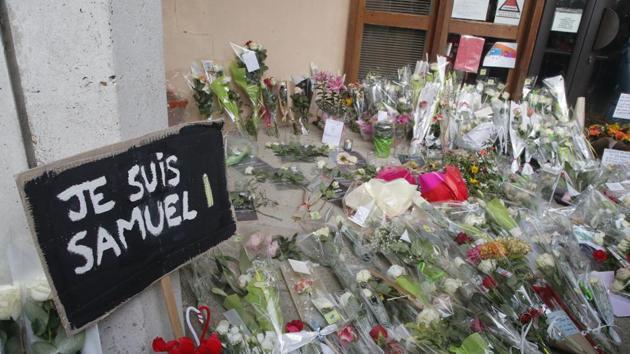 A poster reading "I am Samuel" and flowers lay outside the school where slain history teacher Samuel Paty was working in Conflans-Sainte-Honorine, northwest of Paris. (AP) A poster reading "I am Samuel" and flowers lay outside the school where slain history teacher Samuel Paty was working in Conflans-Sainte-Honorine, northwest of Paris. (AP)