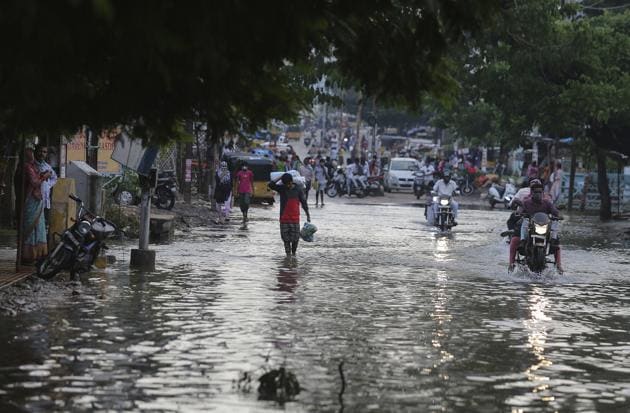 Commuters wade through receding floodwaters after heavy rainfall in Hyderabad on October 15.(AP File Photo)