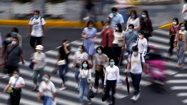 People wearing face masks walk on a street in Shanghai, following the coronavirus disease outbreak, China. (REUTERS) People wearing face masks walk on a street in Shanghai, following the coronavirus disease outbreak, China. (REUTERS)