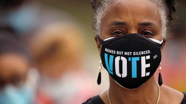 A woman wearing a mask with a message urging voter participation waits in line to enter a polling station on the first day of the state’s in-person early voting for the general election in Durham, North Carolina on October 15. More than 17 million Americans have already cast ballots in the 2020 election, a figure that represents 12% of all the votes cast in the 2016 presidential election. (Jonathan Drake / REUTERS)