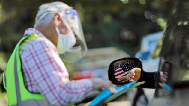 An election worker assists a voter casting her ballot from her car in Durham, North Carolina on October 15. In many critical battleground states, Democrats have “banked” a chunk of their voters and can turn their time and money toward harder to find infrequent voters. (Jonathan Drake / REUTERS)