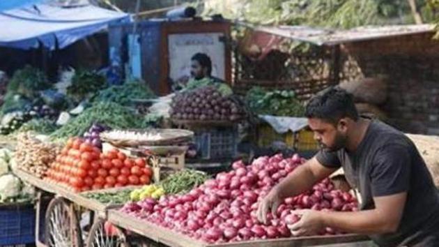 A vegetable vendor awaits customers while arranging onions in his cart at a market in Prayagraj. (AP) A vegetable vendor awaits customers while arranging onions in his cart at a market in Prayagraj. (AP)