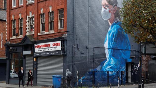 People walk past a mural in Manchester, England on October 19. According to a Reuters tally, worldwide coronavirus cases crossed 40 million on October 19. (Phil Noble / REUTERS)
