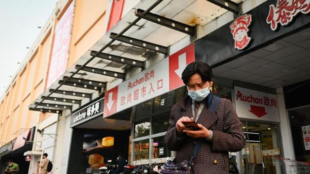 A woman wearing a face mask uses her mobile phone at the entrance of Auchan supermarket in Beijing on October 19, 2020. (AFP Photo) A woman wearing a face mask uses her mobile phone at the entrance of Auchan supermarket in Beijing on October 19, 2020. (AFP Photo)