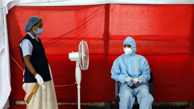 A health worker cools off in front of a fan while working at a Covid-19 testing centre in Pune on October 19. The number of new single day coronavirus infections recorded in the country dropped to below 50,000 for the first time in nearly three months on October 19, data from the Union health ministry showed on October 20. India’s cumulative Covid-19 case tally currently rests at 7.6 million. (Rahul Raut / HT Photo)