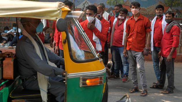 An auto rickshaw moves past coolies wearing face masks outside a railway station in New Delhi on October 17. The health ministry on October 20 also said that the five states most affected by the pandemic have seen a decline in cases since September. The ministry said that the trend of daily cases in Maharashtra, Karnataka, Kerala, Tamil Nadu and Andhra Pradesh reveals various stages of decline in active cases. (Sajjad Hussain / AFP)