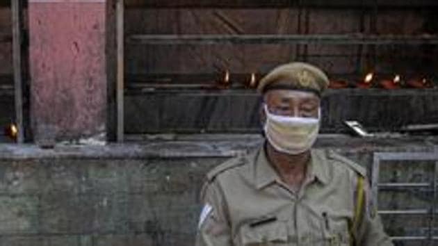 A security person sits wearing mask at the Kamakhya Temple in Assam’s Guwahati in this file photo.(AP Photo)