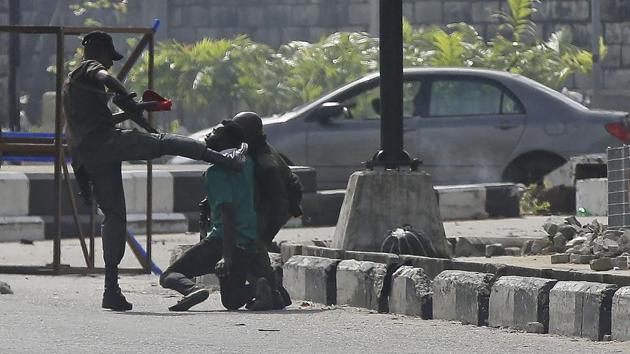 Police personnel detain a protester at the Lekki toll gate in Lagos on October 21. Four witnesses told Reuters that soldiers had fired bullets and at least two people had been shot. Two of the witnesses said the lights were turned off at the gate shortly before the shooting began. (Sunday Alamba / AP)