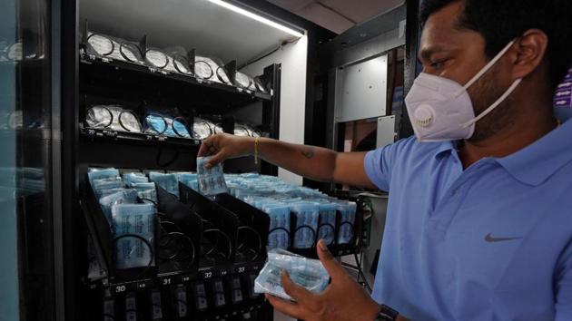 A worker wearing a protective face mask fills a vending machine selling protective face masks and gloves at Dadar railway station. (REUTERS Photo) A worker wearing a protective face mask fills a vending machine selling protective face masks and gloves at Dadar railway station. (REUTERS Photo)