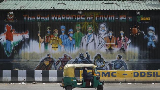 An auto rickshaw drives past a mural depicting frontline workers fighting against Covid-19 in New Delhi.(AP)