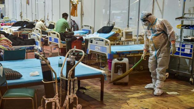 A worker wearing PPE coveralls sweeps the floor at Commonwealth Games village Covid-19 Care Centre in New Delhi on October 18. The testing record follows the trend of an increasing share of RT-PCR tests — they accounted for 28% of the total 59,064 samples tested between October 20 and 21. (Manvender Vashist / PTI)