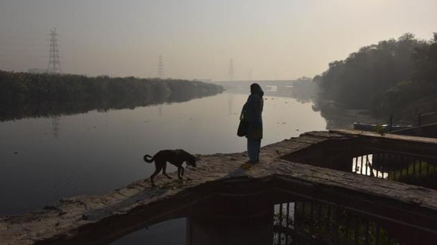 A woman looks on at the Yamuna river standing atop an embankment at Nigambodh Ghat in New Delhi on October 20. The positivity rate — the proportion of tests that come back positive — continued to rise to touch 6.24% on October 21. (Sanjeev Verma / HT Photo)