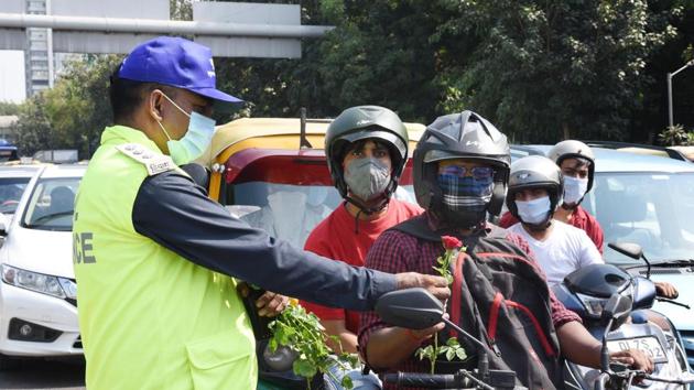 A Civil Defence personnel offers a rose to a commuter during the launch of ‘Red Light On, Gaadi Off’’ campaign at ITO crossing in New Delhi.(Arvind Yadav/HT PHOTO)