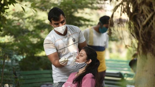 A health worker collects a swab sample from a woman for Reverse Transcription-Polymerase Chain Reaction (RT-PCR) based coronavirus testing in a containment zone in Gurugram on Thursday. (Parveen Kumar/HT) A health worker collects a swab sample from a woman for Reverse Transcription-Polymerase Chain Reaction (RT-PCR) based coronavirus testing in a containment zone in Gurugram on Thursday. (Parveen Kumar/HT)