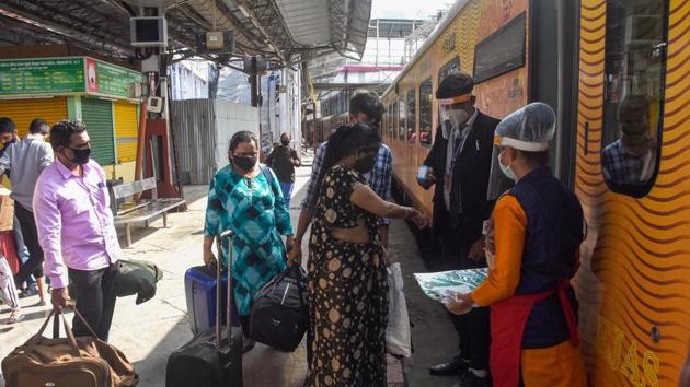Railway staff members distribute PPE kits to passengers before they board Tejas Express train.(PTI)