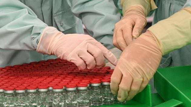 Laboratory technicians handle capped vials as part of filling and packaging tests for the large-scale production and supply of the Oxford University’s Covid-19 vaccine candidate earlier in September.(AFP)