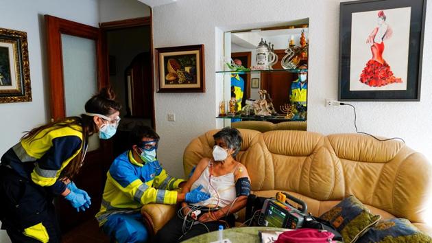 Madrid Emergency Service doctor Carlos Rubio and medical resident Mireya Nadal treat Leoncia, 86, in her home amid the coronavirus outbreak in Madrid on October 19. Desperate to avoid a repeat of the first wave, when the virus ravaged Spain’s elderly population and brought the health service to its knees, several regions have returned to tougher restrictions in recent weeks. (Juan Medina / REUTERS)