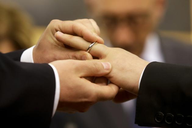 FILE - In this May 21, 2015 file photo, Mauro Cioffari, left, puts a wedding ring on his partner Davide Conti's finger as their civil union is being registered by a municipality officer during a ceremony in Rome's Campidoglio Capitol Hill. In the film, Pope Francis said, “You can’t kick someone out of a family, nor make their life miserable for this. What we have to have is a civil union law; that way they are legally covered.” (AP)
