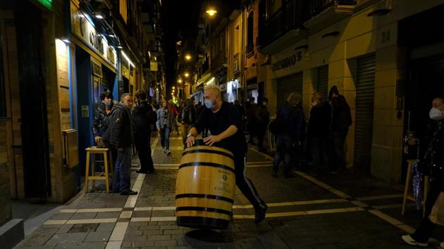 A worker prepares to close a bar in Pamplona as new restrictions come into effect on October 21. After being brought under control during the nationwide lockdown in the spring, the virus started spreading again a couple of months after restrictions were lifted and people started to move around and socialize again. (Alvaro Barrientos / AP)