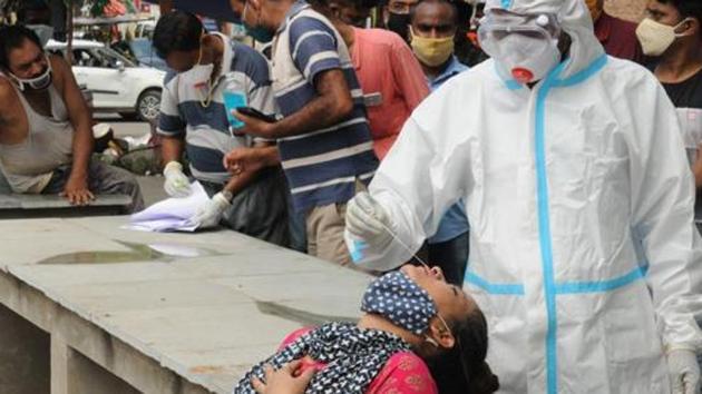 Health worker in PPE kit collects swab sample at the market at Boring road for Covid 19 test, in Patna, Bihar. (HT photo)