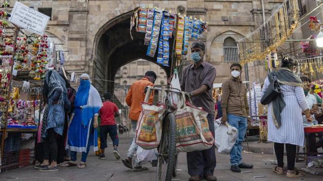 A vendor wearing a protective mask wheels a bicycle past stalls at the Bhadra Fort market in Ahmedabad, India on October 22. Within the region, South Asia led by India is the worst affected, with nearly 21% of the reported global coronavirus cases and 12% of deaths. (Sumit Dayal / Bloomberg)