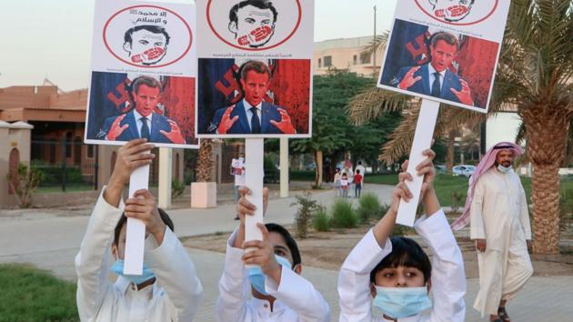 In picture - Kuwaiti youths lift placards expressing anger at French President Emmanuel Macron at a rally in front of the country's National Assembly (parliament) in Kuwait City.(AFP)