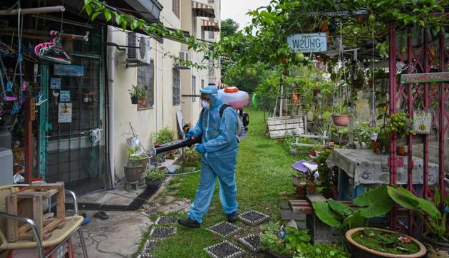 A city council volunteer worker wearing protective gear sprays disinfectant, amid the Covid-19 coronavirus pandemic, in the backyard of an apartment building in Kuala Lumpur on October 26, 2020.(AFP photo)