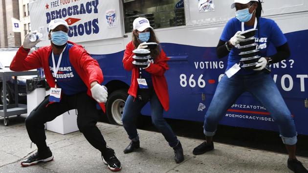 ‘Pizza to the Polls’ food truck staff dance for the voters queueing outside a polling station on early voting day in New York on October 24. The tally by the independent US Election Project, run by the University of Florida, said that as of October 25 more than 59 million people had voted, AFP reported. (Jason DeCrow / AP)