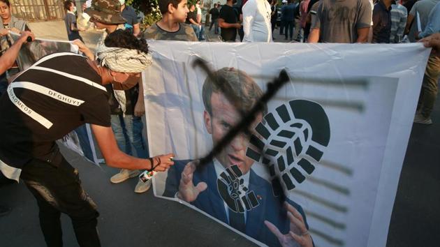 Protesters deface a picture of French President Emmanuel Macron during a protest over caricatures of the Prophet Muhammad.(AP) Protesters deface a picture of French President Emmanuel Macron during a protest over caricatures of the Prophet Muhammad.(AP)