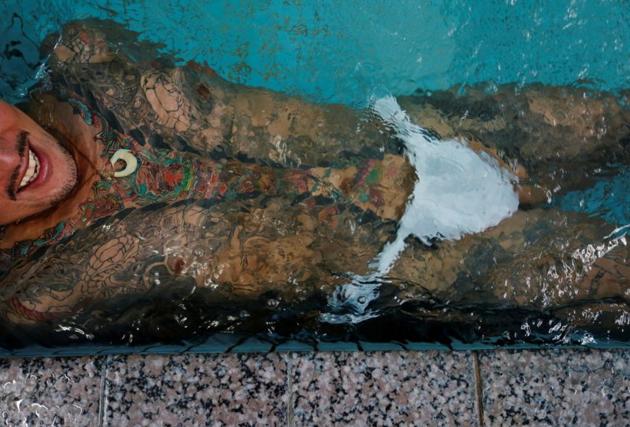 Restaurant owner Hiroshi Sugiyama, 38, lies in the water at a Japanese public bath called a "sento", as he gets together with tattoo artist Asakusa Horikazu to pose for photographs in Tokyo, Japan, September 24, 2020. (REUTERS)
