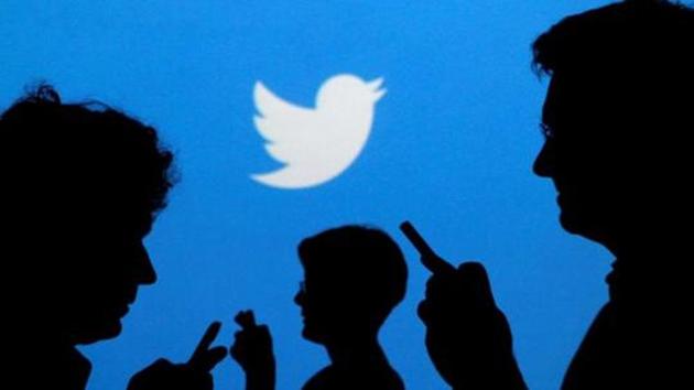 People holding mobile phones are silhouetted against a backdrop projected with the Twitter logo in this illustration picture.(Reuters)