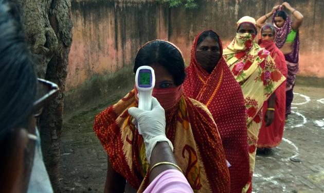 Voters are thermal screened before proceeding to cast their votes in the during the first phase of Bihar Assembly elections, in Patna on October 28. A stringent nationwide lockdown imposed in March has gradually been eased and life across the country is edging back to pre-virus levels with lockdowns now restricted only to containment zones. (Parwaz Khan / HT Photo)