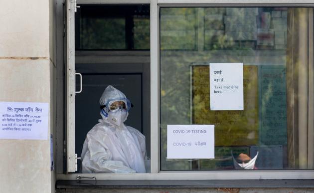 A health worker look out from a sample collection window at a Covid-19 testing facility in Chandigarh on October 27. While businesses and theatres have slowly started to reopen, schools and colleges remain shut in most cities. Gatherings for upcoming festivals, the advent of colder temperatures and the annual winter pollution crisis loom as causes of a spurt in infections. (Ravi Kumar / HT Photo)