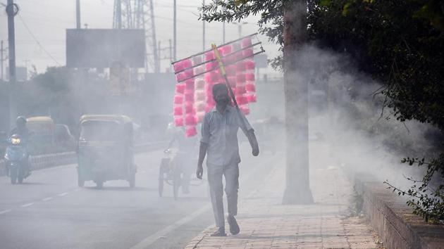 A candy floss vendor walks amid smoke wafting from a fire in Chilla Village near Mayur Vihar on October 27. According to doctors, the deteriorating air quality has already caused a spike in respiratory infections, Reuters reported. (Raj K Raj / HT Photo)