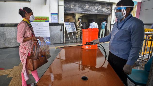 A security guard sprays sanitizer on the luggage of a passenger during the resumption of metro service, in New Delhi (Photo by Biplov Bhuyan/ Hindustan Times)