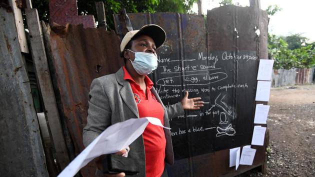 Educator Taneka Mckoy Phipps teaches a lesson next to a blackboard painted on a zinc fence.(REUTERS) Educator Taneka Mckoy Phipps teaches a lesson next to a blackboard painted on a zinc fence.(REUTERS)