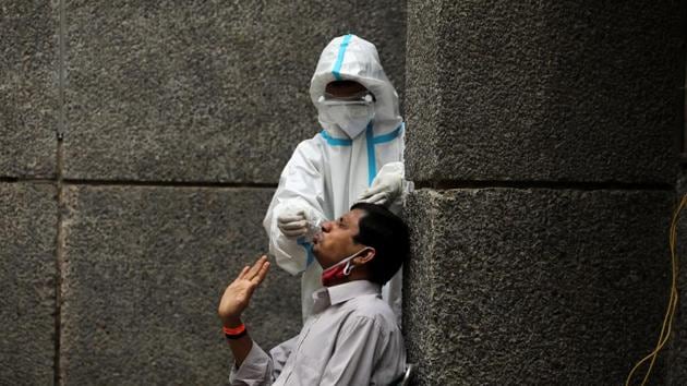 A health care worker wearing personal protective equipment (PPE) collects a swab sample from a man amid the spread of Covid-19 at a testing centre in Delhi.(Reuters Photo) A health care worker wearing personal protective equipment (PPE) collects a swab sample from a man amid the spread of Covid-19 at a testing centre in Delhi.(Reuters Photo)