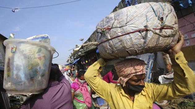 A porter wearing a face mask navigates his way through a crowded market area in Bengaluru on October 29. Despite a steady decline in recent weeks from mid-September peaks just shy of the 100,000 mark, the number of daily cases logged in the last 24 hours at 49,881, marks a significant increase on the 36,470 cases reported two days ago, which was the lowest daily infection count since July 18. (Aija Rahi / AP)