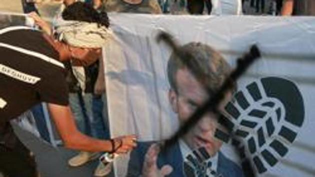 Protesters deface a picture of French President Emmanuel Macron during a protest over caricatures of the Prophet Muhammad they deem insulting and blasphemous, outside the French Embassy, in Baghdad, Iraq, Monday, October 26, 2020.(AP file photo)