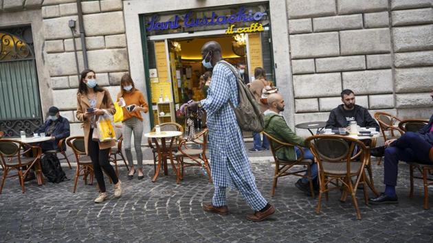A street vendor tries to sell his goods in front of a cafe', in Rome, Monday, Oct. 26, 2020.(AP photo) A street vendor tries to sell his goods in front of a cafe', in Rome, Monday, Oct. 26, 2020.(AP photo)