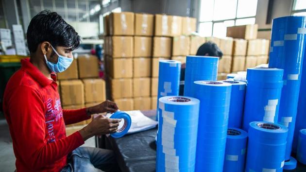 A worker wearing a protective masks packs a roll of adhesive sealing tape at a factory in Sonipat district, Haryana.(Bloomberg File Photo)