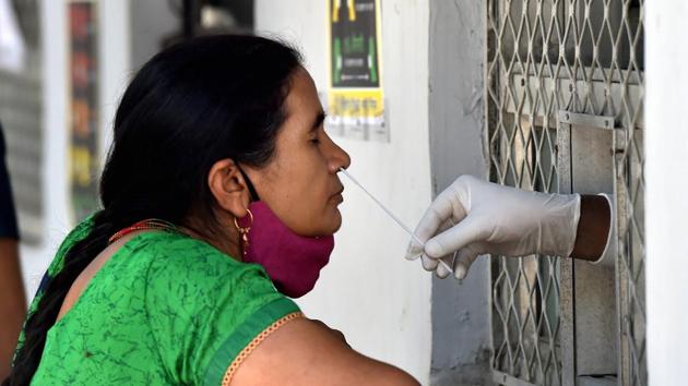 A health worker collects a sample from a woman for COVID-19 test, at a dispensary in New Delhi on Saturday.(PTI) A health worker collects a sample from a woman for COVID-19 test, at a dispensary in New Delhi on Saturday.(PTI)