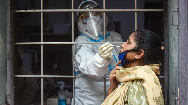 A health worker in PPE coveralls collects a swab samples for coronavirus test at Amar Colony in New Delhi on Thursday.(Amal KS/HT Photo)