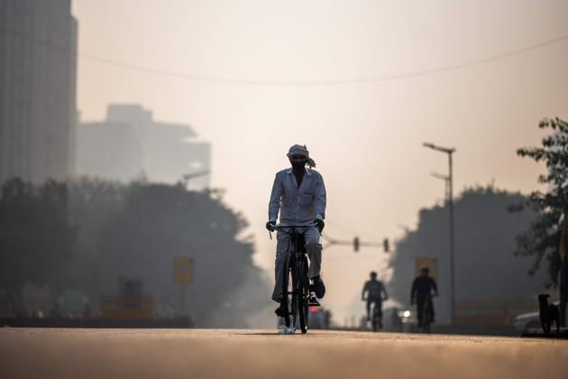 A man wearing a facemask rides his bicycle along a street amid smoggy condition in New Delhi on October 30.(AFP)