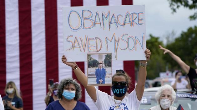 Adelys Ferro holds a sign in support of Obamacare as former President Barack Obama speaks while campaigning for Democratic presidential candidate former Vice President Joe Biden at Florida International University, Saturday, Oct. 24, 2020, in North Miami, Fla. (AP Photo/Lynne Sladky)(AP) Adelys Ferro holds a sign in support of Obamacare as former President Barack Obama speaks while campaigning for Democratic presidential candidate former Vice President Joe Biden at Florida International University, Saturday, Oct. 24, 2020, in North Miami, Fla. (AP Photo/Lynne Sladky)(AP)