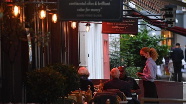 A waitress takes an order from diners sitting outside a restaurant in central London on November 1. Non-essential shops, leisure and entertainment venues will all be closed and pubs, bars, restaurants must close except for takeaway and delivery services. Workplaces are expected to stay open where people can’t work from home, such as in the construction or manufacturing sectors. (Justin Tallis / AFP)